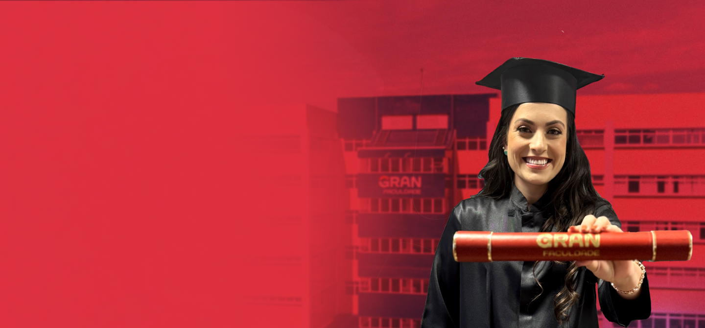 Jovem mulher de cabelos longos e castanhos, sorridente, vestindo beca e capelo, segurando um canudo de formatura vermelho com o logo da Gran Faculdade. Ao fundo, o prédio da instituição em Curitiba, com tons de vermelho em destaque.